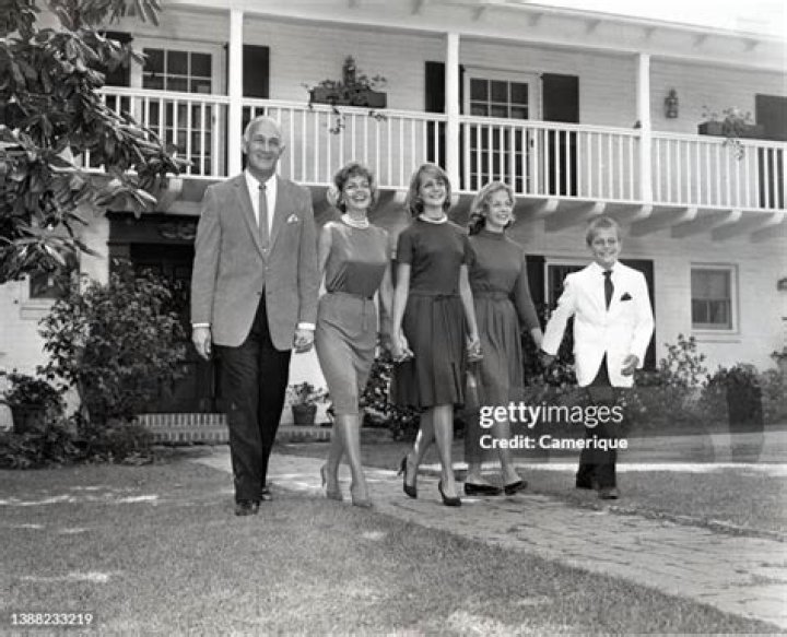 Tom Harmon family walking in front of their house holding hands